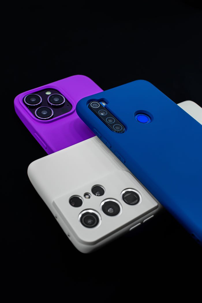 Three colorful smartphones with various camera designs on a dark surface.